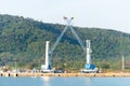 Heavy lifting tower mobile crane for loading cargo in the small commercial sea port with moutain view in the background