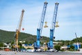 Heavy lifting tower mobile crane for loading cargo in the small commercial sea port with moutain view in the background