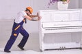 Heavy loads concept. Loader moves piano instrument. Courier delivers furniture, move out, relocation. Man with beard Royalty Free Stock Photo