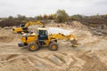 Heavy machinery is actively working at a construction site in autumn. A loader and an excavator are moving sand and dirt under Royalty Free Stock Photo