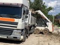 Heavy machinery at a construction site. Loader and truck during unloading. Unloading of building materials