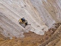 Heavy machinery working at the bottom of an open pit mine on a day with a lot of fog and rain