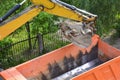 Heavy machinery working on construction site - excavator loading dump trucks during roadworks at highway. Heavy duty machinery