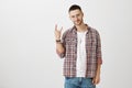 Heavy metal break my heart. Studio shot of handsome joyful bearded guy showing rock sign while standing over gray Royalty Free Stock Photo