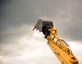 Heavy orange excavator arm reaches the sky