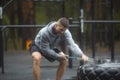 Heavy outdoor training on a rainy day - a man hits a tire with a sledgehammer. Royalty Free Stock Photo