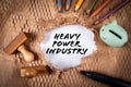 Heavy Power Industry. Piggy bank and office supplies on cardboard background