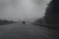 Heavy rain on the highway, blurred cars with red taillights, drops and water on the dark road, dangerous weather while driving, Royalty Free Stock Photo