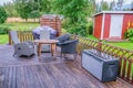 Heavy rain at wooden terrace with summer chairs, wooden table. Blurry green forest at background. Everything is very wet. Royalty Free Stock Photo