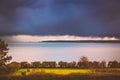 Heavy rainclouds over the horizon and Deal and Sandwich in Kent, Uk whilst the sunshine on a park area of the Royal Esplanade,