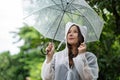 Heavy rainy day. Happy asian woman wearing raincoat and holding umbrella outdoors Royalty Free Stock Photo