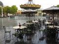 Heavy rainfall in theme park, deserted outdoor seating places and swing ride