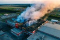 Heavy smoke in burning industrial warehouse or storehouse industrial hangar from burned roof, aerial view of fire disaster Royalty Free Stock Photo