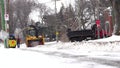 A heavy machinery plowing and blowing the snow after a snowstorm to the sidewalk