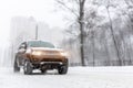 Heavy snowfall and blurred SUV awd car on road. 4wd vehicle on city street at winter. Seasonal roadside assistance concept. Royalty Free Stock Photo