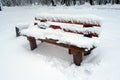 After a heavy snowfall, a city bench in the park.