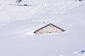 Heavy snowfall covering the mountain house up to the roof. Untouched deep white pure snow drifts in winter Alps Royalty Free Stock Photo