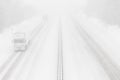 Heavy snowfall on the highway. Dangerous winter weather with low visibility. White cargo truck on the freeway Royalty Free Stock Photo