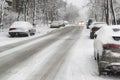 Heavy snowfall and slippery road with parked cars