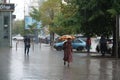 Heavy summer rain in Kyiv. People walks under umbrellas along wet streets