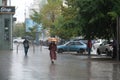 Heavy summer rain in Kyiv. People walks under umbrellas along wet streets