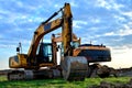 Heavy tracked excavator at a construction site on a background of a residential building and construction cranes on a sunny day Royalty Free Stock Photo