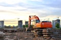 Heavy tracked excavator at a construction site on a background of a residential building and construction cranes on a sunny day Royalty Free Stock Photo