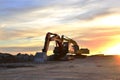 Heavy tracked excavators at a construction site on a background sunset.