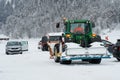 Heavy tractor with rear dozer blade in parking lot with cars in cross country skiing resort in Switzerland