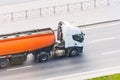 Heavy truck with a tank for flammable liquids rides on the road, close up view Royalty Free Stock Photo