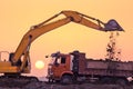 Heavy wheel excavator machine working at sunset