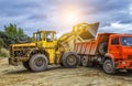 heavy wheel excavator machine working at sunset, loads the sand into the truck Royalty Free Stock Photo