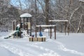 Snow-covered playground in a residential area with children playing