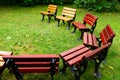 Wood and cast iron garden chairs placed in circle with green grass Royalty Free Stock Photo