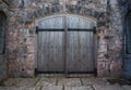 Heavy wooden castle double door with metal bands and studs.  Medieval style set in a stone block wall Royalty Free Stock Photo