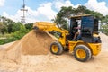 Heavy yellow bulldozer on construction. Wheel loader machine unloading sand