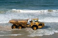 Heavy yellow dump truck working on the sea beach