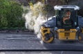 Heavy yellow shovel or Road roller rolls flat the asphalt on a road