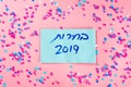 Hebrew text :Elections 2019 on voting paper over pink with colorful confetti background. Royalty Free Stock Photo