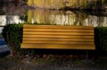 Hedge of boxwood and pine tree trunk by the road in the park with curved benches by the pond. wood paneled entice you to sit down.