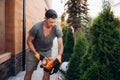 Hedge Trimmer Works. Gardener with Gasoline Hedge Trimmer Shaping Wall of Thujas Royalty Free Stock Photo