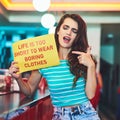 Heed this message. an attractive young woman holding up a sign in a retro diner.