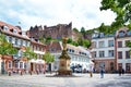Square called `Kornmarkt` in old city center with people walking by, fountain with golden Madonna statue and view on historical He