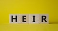 Heir symbol. Concept word Heir on wooden cubes. Beautiful yellow background. Business and Heir concept. Copy space