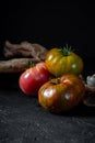 Heirloom tomatoes. Three tomatoes of different colors and a beautiful snag on a black background