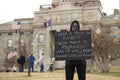 Helena, Montana - April 19, 2020: A female protestor wear all black with a bandana mask and holding sign about loss of life,