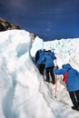 Hikers in single file ascending rugged icy slope at glacier exploration