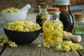 Helichrysum arenarium infusion bottle and dwarf everlast or immortelle dried flowers in bowl on wooden table. Tinctures and oil