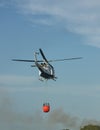 A helicopter collaborates in the extinction of a fire carrying the Bambi bucket System Royalty Free Stock Photo