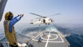 Helicopter deck officer give hand signal to Sikorsky S-70 Sea Hawk helicopter hovering above helicopter deck of Thai Navy ship